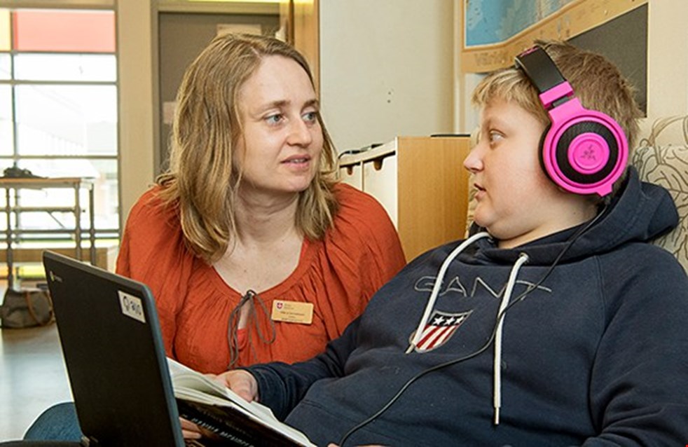 Bild på en lärare och en elev med hörlurar.