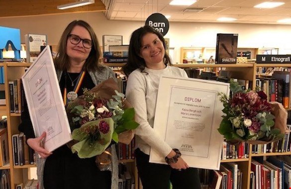 Kajsa Bergh  och Ma ria  Lorentzon är  Årets läsombud  2021 De står med sina diplom framför en bokhylla.