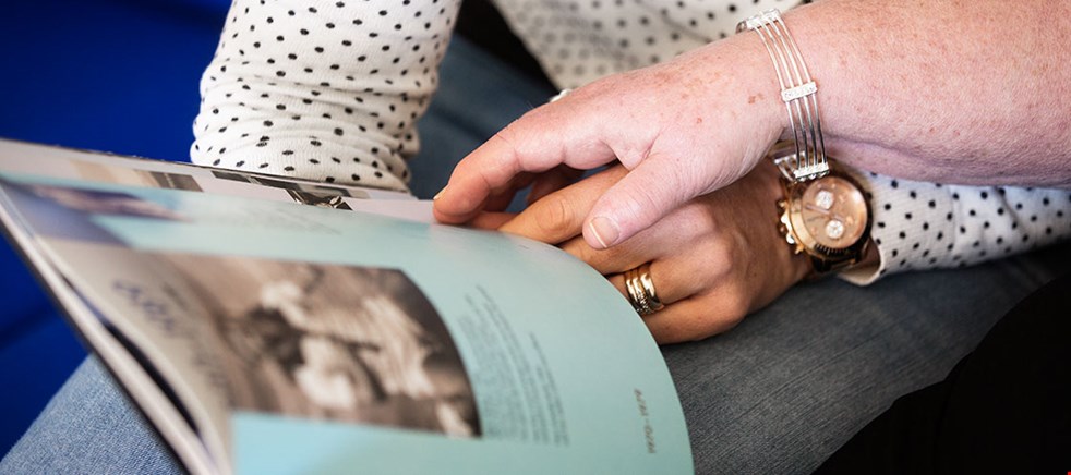 Bild på en kvinna och en äldre kvinna som läser tillsammans håller händer.s och 